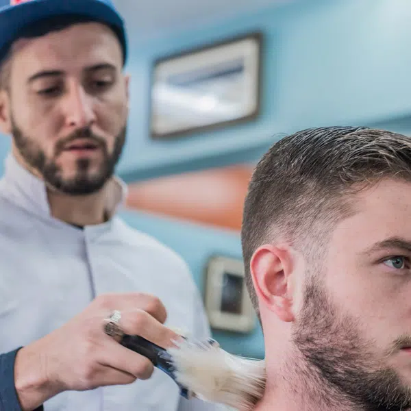 Barbeiro finalizando o corte de um cliente.